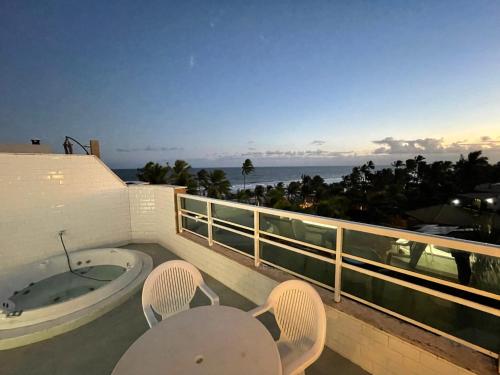 un balcón con bañera de hidromasaje, sillas y el océano en Apart-hotel 02 Quartos com cobertura - Frente Mar - Vilas do Atlântico, en Lauro de Freitas