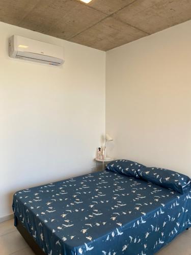 a bedroom with a bed with a blue comforter at Monoambiente a estrenar con BALCÓN y DECK in La Plata