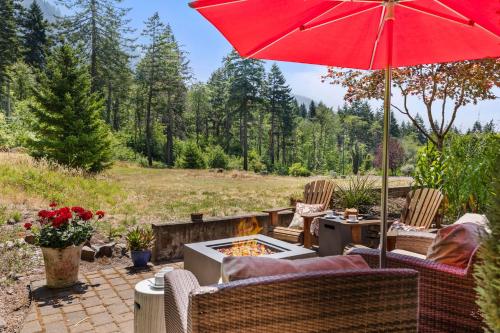 a patio with a fire pit and a red umbrella at Mountain-View Retreat with Hot Tub & Waterfalls in Cascade Locks