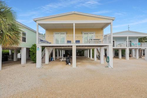 a large yellow house with a large deck at Navigate Stays Florida Keys Home with Private Dock in Crawl Key Number Two