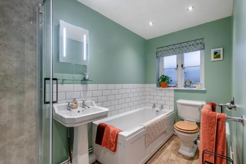 une salle de bain avec une baignoire, un lavabo et des toilettes dans l'établissement Blacksmiths Cottage - Buxton Norfolk, à Buxton