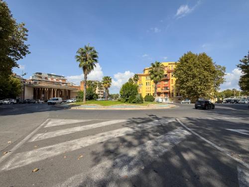 an empty street with a building and palm trees at Marina - appartamento in centro al mare Ostia in Lido di Ostia