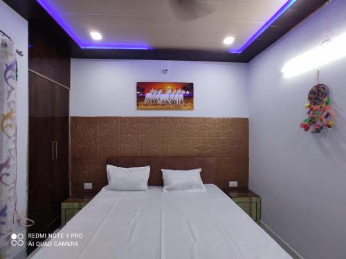 a bedroom with a large white bed with purple lights at Shri laddu Gopal dham in Chhatikara