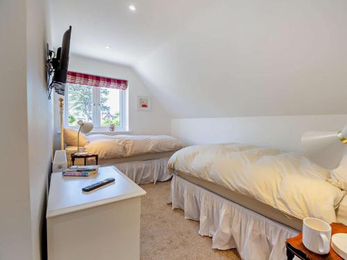 a bedroom with two beds and a desk and a window at 4 Bed in Saint Asaph 96246 in St Asaph