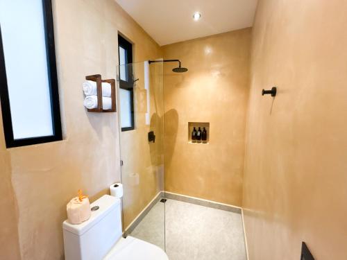 a bathroom with a toilet and a glass shower at Ana y Jose Hotel & Beach Club Holbox in Holbox Island