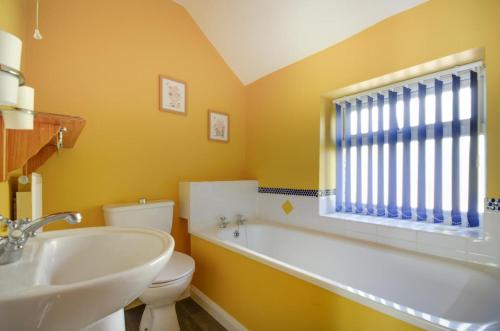 un bagno con vasca, lavandino e WC di Owl Cottage a Holt