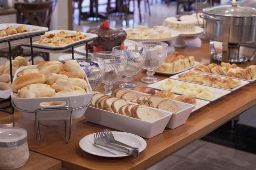 a table filled with different types of bread and pastries at Castelo Inn Hotel in Goiânia
