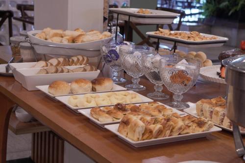 a table with several trays of bread and pastries at Castelo Inn Hotel in Goiânia