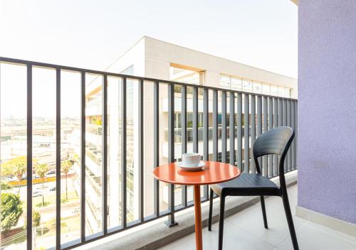 a table and a chair on a balcony with a view at Charlie Aeroporto Congonhas CGH in Sao Paulo