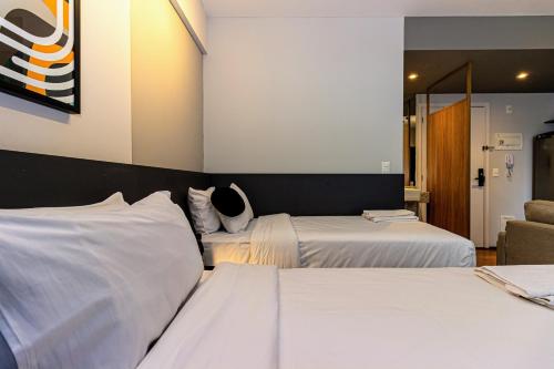 a hotel room with two beds and a chair at Charlie Aeroporto Congonhas CGH in Sao Paulo