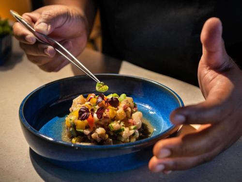 a person is eating a bowl of food with chopsticks at Novotel Suites Paris CDG Airport Villepinte in Roissy-en-France