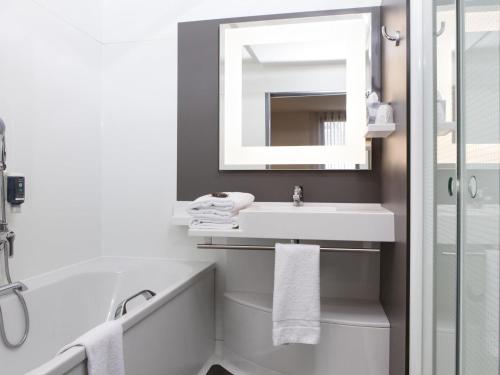 a bathroom with a sink and a tub and a mirror at Novotel Suites Paris Stade de France in Saint-Denis