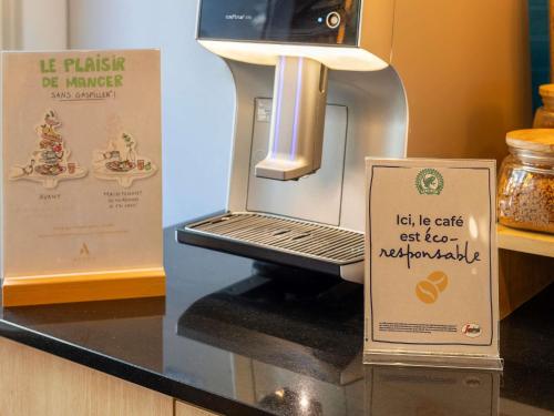 a display case with a coffee machine with a sign at Novotel Suites Paris Stade de France in Saint-Denis