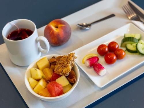 a tray with a bowl of fruit and a cup of coffee at Novotel Suites Paris Stade de France in Saint-Denis
