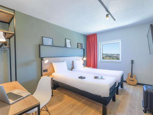 a hotel room with a bed and a desk and a laptop at Hotel ibis Bragança in Bragança