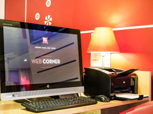a computer monitor and a printer on a desk at ibis Porto Centro São Bento in Porto