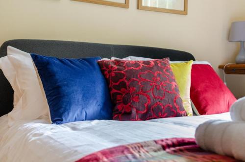 a bed with colorful pillows on top of it at St Lawrence House in Harpley