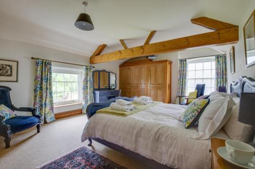 a bedroom with a bed and a chair and windows at St Lawrence House in Harpley