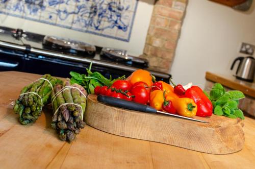 a wooden bowl of fruits and vegetables on a table at St Lawrence House in Harpley