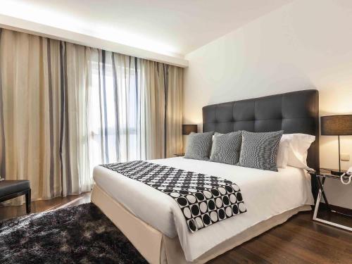 a bedroom with a large bed and a large window at Hotel Mercure Lisboa in Lisbon
