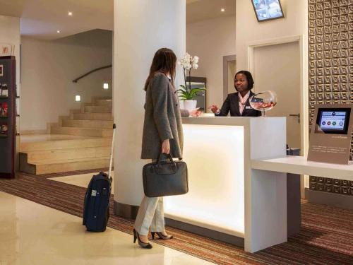 a woman standing at a counter in a store at Hotel Mercure Lisboa in Lisbon