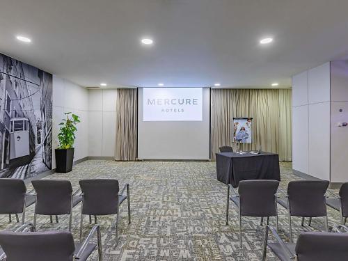 a meeting room with a table and chairs and a screen at Hotel Mercure Lisboa in Lisbon