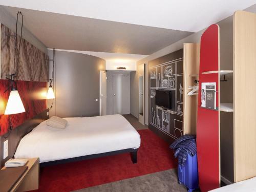 a hotel room with a large bed and a red carpet at ibis Cholet in Cholet
