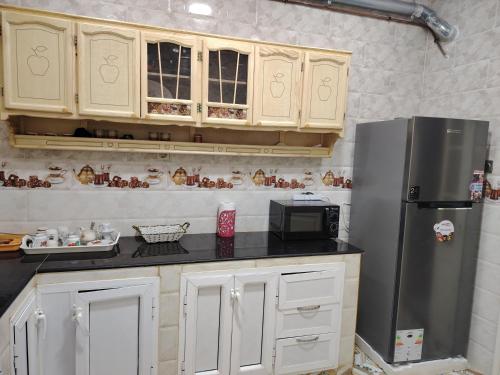a kitchen with white cabinets and a stainless steel refrigerator at Appt F4 equipé au rez de chaussé d'un immeuble privé in Skikda