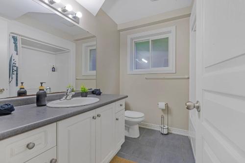 a white bathroom with a sink and a toilet at Niagara Retreat|HotTub|Sauna|Games|15 Min to Falls in Thorold
