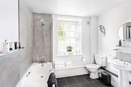 a bathroom with a tub and a toilet and a sink at The Old Toffee Works, Montpellier Quarter, Next to Pump Rooms FREE PARKING in Harrogate