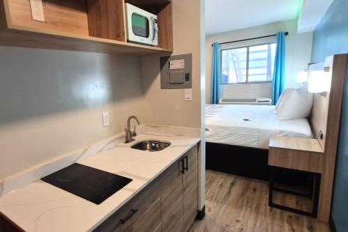 a small kitchen with a sink and a bed at Exclusivo Inn by OYO Grand Prairie, TX in Grand Prairie