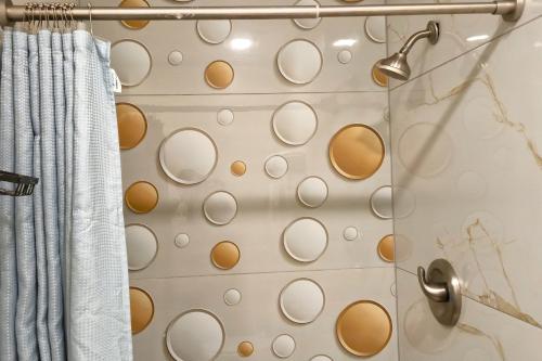 a shower with aige and white circles on the wall at Exclusivo Inn by OYO Grand Prairie, TX in Grand Prairie