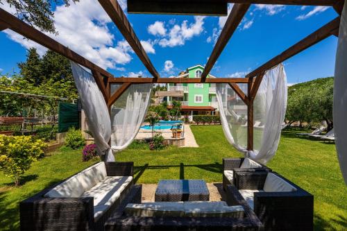 a backyard with a pergola with couches and a pool at MY DALMATIA - Villa Green Paradise with private heated swimming pool in Peračko Blato