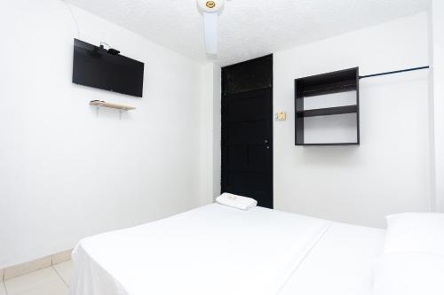 a white room with a bed and a black door at Hotel Costa Caribe BAQ in Barranquilla