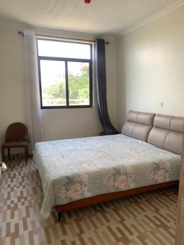 ein Schlafzimmer mit einem großen Bett mit einem großen Fenster in der Unterkunft Verdant Treehouse in Kigali