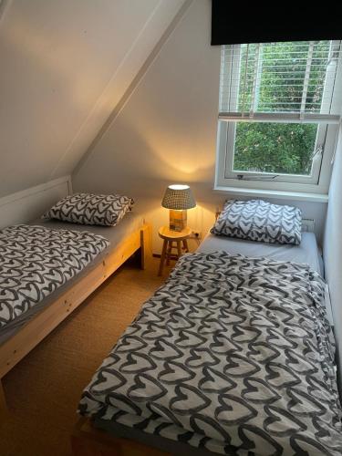 a bedroom with two beds and a window at 6 persoons Vakantiehuis Lavendel in Zeeland in Zonnemaire