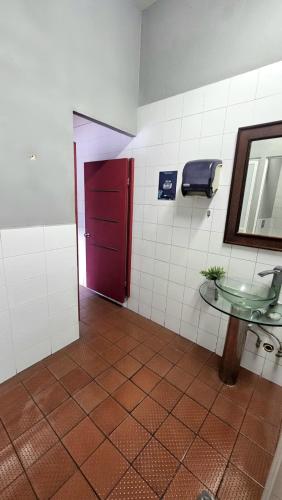a bathroom with a sink and a red door at Hostel Auikyani in Cozumel