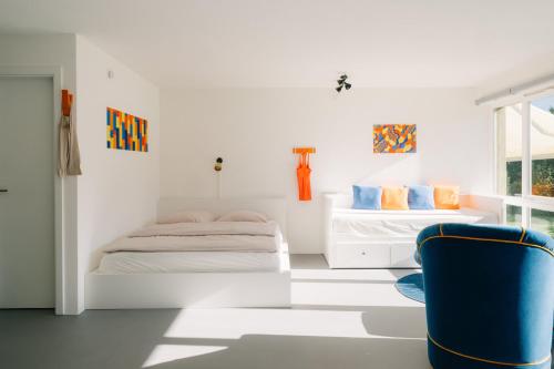 a bedroom with two beds and a blue chair at Apartment Baytrail in Seenähe in Spiez