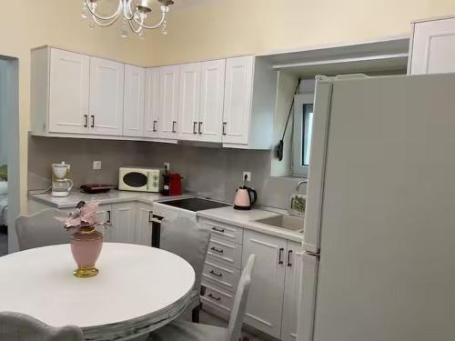 a kitchen with white cabinets and a table with a vase on it at Niki's Dream House in Ierápetra