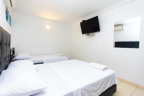 two beds in a room with a tv on the wall at Hotel Costa Caribe BAQ in Barranquilla