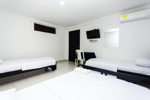 a room with two beds and a chair in it at Hotel Costa Caribe BAQ in Barranquilla