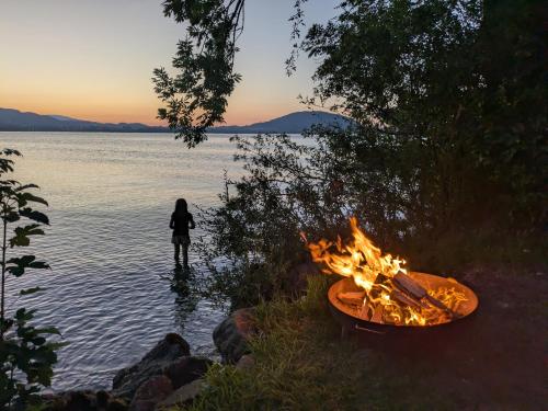 a woman standing in the water next to a campfire at Bachbauer am Attersee in Weyregg