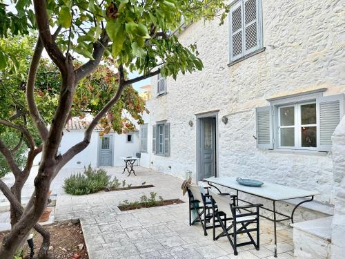 a patio with a table and chairs in front of a building at Kaminēa in Hydra