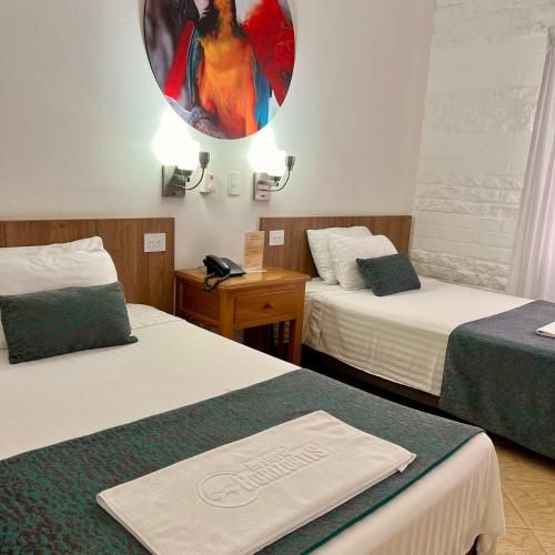 a hotel room with two beds and a mirror at Hostería Horizontes in Caucasia