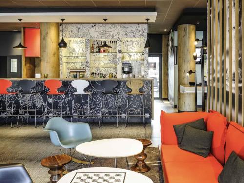 a restaurant with orange couch and chairs and a bar at ibis Hotel Hannover City in Hannover