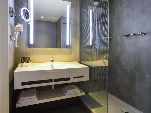 a bathroom with a sink and a shower at Novotel Szczecin Centrum in Szczecin