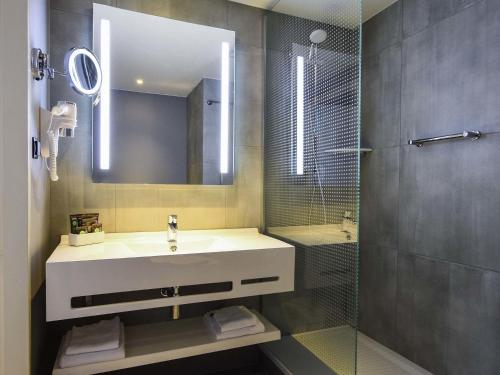 a bathroom with a sink and a shower with a mirror at Novotel Szczecin Centrum in Szczecin
