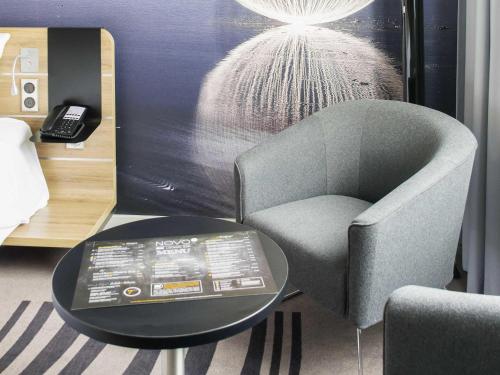 a chair and a table in a room at Novotel Szczecin Centrum in Szczecin