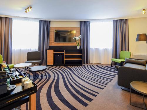 a living room with a couch and a tv at Novotel Szczecin Centrum in Szczecin