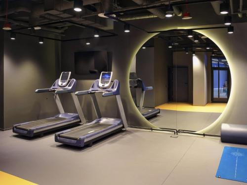 a gym with three treadmills and a mirror at Novotel Szczecin Centrum in Szczecin